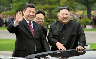 オープンカーから沿道の市民に手を振る習近平国家主席と金正恩委員長(右)(20日、平壌)=朝鮮中央通信・共同 オープンカーから沿道の市民に手を振る習近平国家主席と金正恩委員長(右)(20日、平壌)=朝鮮中央通信・共同