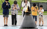 平和祈念公園を訪れ、「平和の火」の前で手を合わせる人たち（23日、沖縄県糸満市）