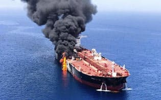 13日、ホルムズ海峡付近で攻撃を受けて火災を起こし、オマーン湾で煙を上げるタンカー=AP 13日、ホルムズ海峡付近で攻撃を受けて火災を起こし、オマーン湾で煙を上げるタンカー=AP