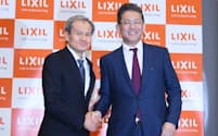記者会見で握手するLIXILグループの瀬戸欣哉CEO(右)と松崎正年取締役会議長（25日、東京都中央区）