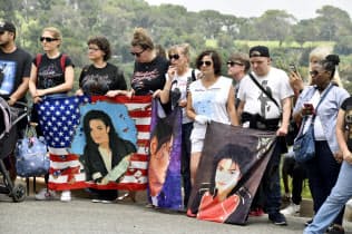 マイケル・ジャクソンさんの墓地前で似顔絵を掲げるファンら(25日、米カリフォルニア州グレンデール)=共同 マイケル・ジャクソンさんの墓地前で似顔絵を掲げるファンら(25日、米カリフォルニア州グレンデール)=共同