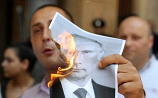 ロシアのプーチン大統領の写真を燃やすジョージアのデモ参加者(6月20日、トビリシ)=ロイター ロシアのプーチン大統領の写真を燃やすジョージアのデモ参加者(6月20日、トビリシ)=ロイター