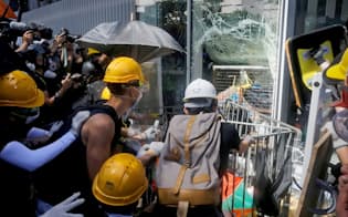 立法会（議会）の窓ガラスを破壊しようとする若者ら（1日、香港）=ロイター