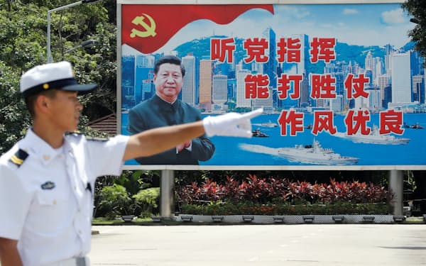習国家主席の看板の前に立つ中国人民解放軍の兵士（2019年6月30日、香港）=ロイター