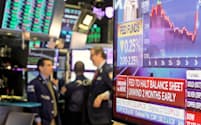 ニューヨーク証券取引所で利下げを伝えるニュース画面（31日）=ロイター