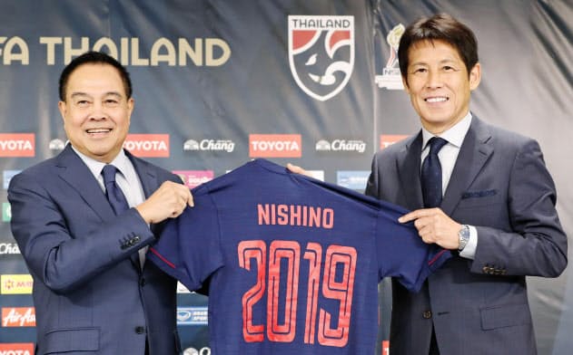 タイ代表監督に就任し、ユニホームを手にポーズをとる西野朗氏。左はタイ・サッカー協会のソムヨット会長(7月19日)=共同 タイ代表監督に就任し、ユニホームを手にポーズをとる西野朗氏。左はタイ・サッカー協会のソムヨット会長(7月19日)=共同