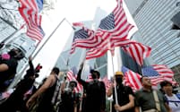 米国旗を掲げ行進するデモ参加者（8日、香港）=ロイター