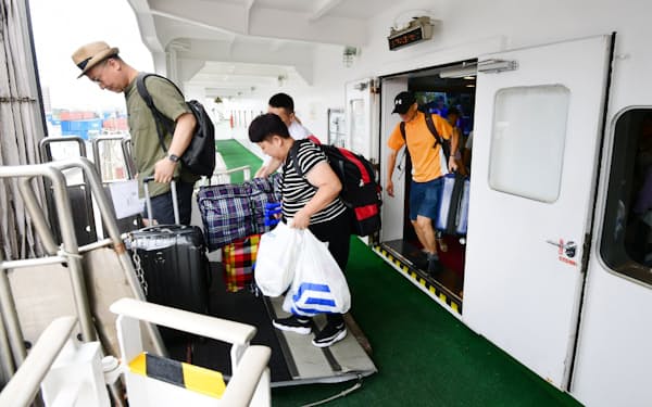 多くの荷物を抱えて新鑑真号から下船する乗客（8月、大阪市）