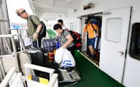 多くの荷物を抱えて新鑑真号から下船する乗客（8月、大阪市）