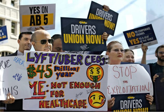 カリフォルニア州で成立した新法により、ウーバーやリフトは運転手を「従業員」として扱わなければならなくなる見込みだ(写真は新法成立を求めていた活動家ら)=AP カリフォルニア州で成立した新法により、ウーバーやリフトは運転手を「従業員」として扱わなければならなくなる見込みだ(写真は新法成立を求めていた活動家ら)=AP