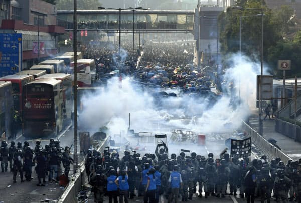 香港で「逃亡犯条例」改正案を発端とした抗議活動をするデモ隊(奥)に、警官隊が催涙弾を撃ち込み現場に立ち込める煙(1日)=共同