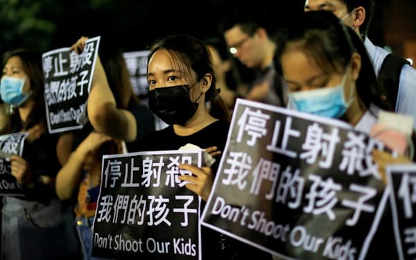 「私たちの子どもを撃つな」と書かれた紙を掲げる人たち（2日、香港）=ロイター