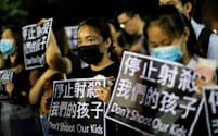 「私たちの子どもを撃つな」と書かれた紙を掲げる人たち（2日、香港）=ロイター