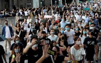 4日、覆面禁止規則に反対し、香港中心部をデモ行進するマスク姿の参加者ら=ロイター