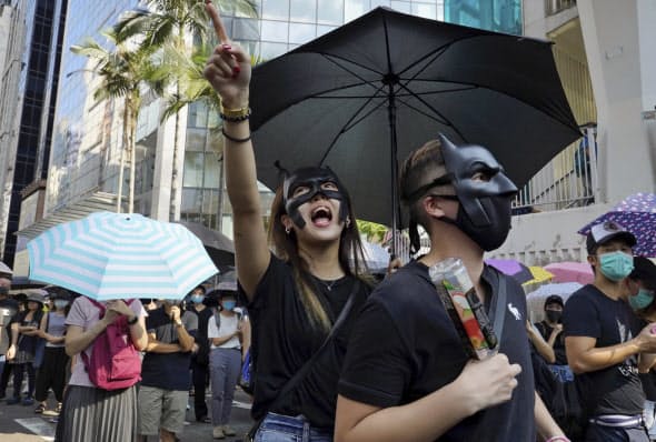 「覆面禁止規則」に反対し、マスク姿でデモ行進する若者ら（5日、香港）=AP