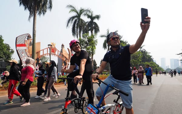 英国製の折りたたみ自転車に乗りながら、SNSで写真を共有する(ジャカルタ中心部)