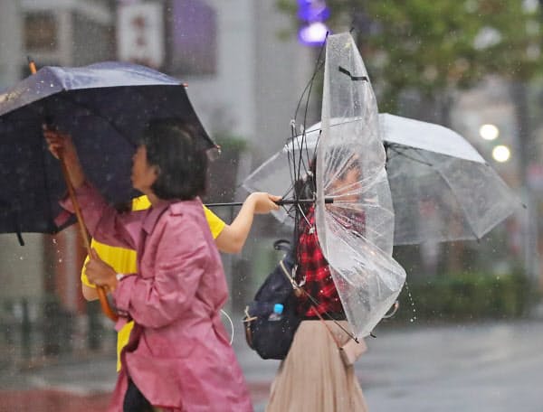 強風のなかを歩く人たち(12日午後、東京都新宿区)