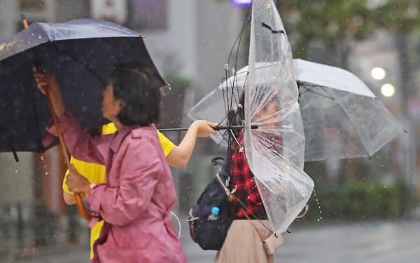 強風の中を歩く人たち(12日、東京都新宿区)