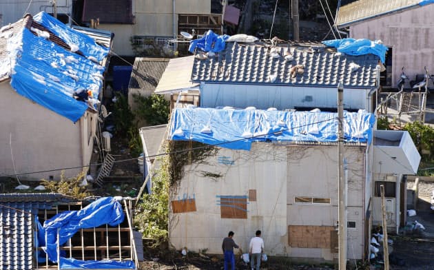 台風19号の暴風雨で剥がれ落ちた屋根のブルーシート。先の台風15号で受けたとみられる被害が今も残る(13日午前、千葉県鋸南町)=共同 台風19号の暴風雨で剥がれ落ちた屋根のブルーシート。先の台風15号で受けたとみられる被害が今も残る(13日午前、千葉県鋸南町)=共同