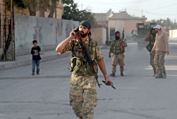 シリア北部テルアビヤドを歩くトルコ軍側のシリア反体制派兵士(13日)=ロイター