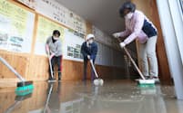 学校再開に向け、校舎に入り込んだ泥をかき出す人たち（16日、長野市の東北中学校）=山本博文撮影