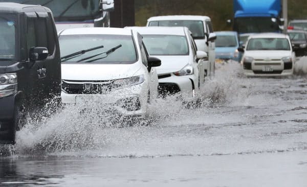 大雨の影響で道路が冠水し、水しぶきを上げて走る車(25日、千葉県君津市)