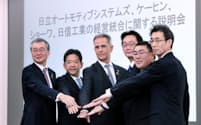 傘下の部品メーカーの統合を発表し握手する日立製作所の小島副社長（左端）ら（30日、東京都台東区）