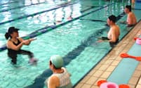 インストラクター(左)の掛け声に合わせて水中で体を動かす高齢者（埼玉県蕨市の「ルネサンス蕨24」）
