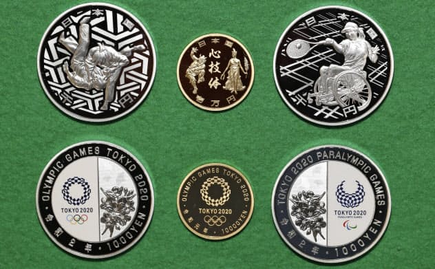 2020年の東京五輪を記念した千円銀貨(左)、1万円金貨(中央)、パラリンピックを記念した千円銀貨。上が表(8日午後、大阪市の造幣局)=共同 2020年の東京五輪を記念した千円銀貨(左)、1万円金貨(中央)、パラリンピックを記念した千円銀貨。上が表(8日午後、大阪市の造幣局)=共同