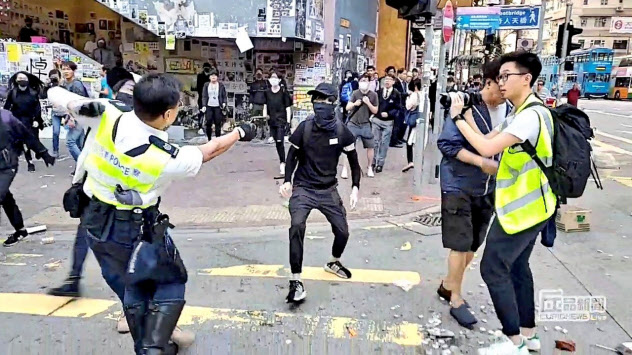 11日、西湾河でデモ参加者に拳銃を向ける警官=丘品新聞・ロイター 11日、西湾河でデモ参加者に拳銃を向ける警官=丘品新聞・ロイター