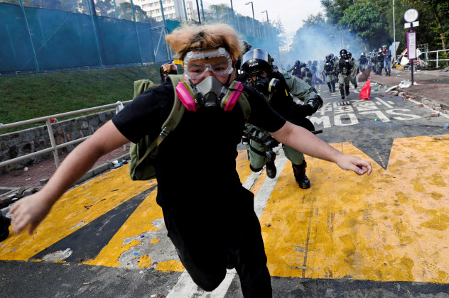 12日、香港中文大学のキャンパスで警察に追われて逃げる学生=ロイター 12日、香港中文大学のキャンパスで警察に追われて逃げる学生=ロイター