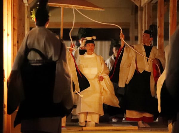 薄明かりの中、「悠紀殿供饌の儀」のため、祭服を着て悠紀殿に向かう天皇陛下(14日、皇居・東御苑)=代表撮影