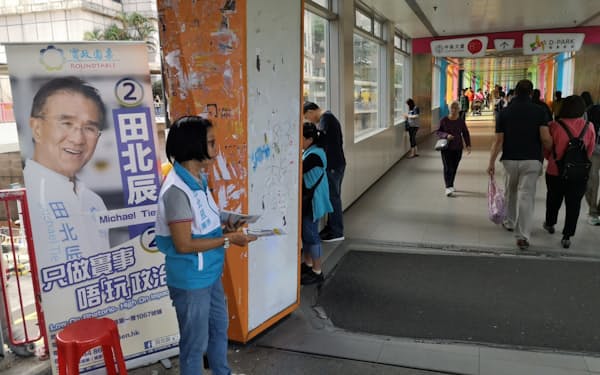 チラシを配る候補者のスタッフ（23日、香港）