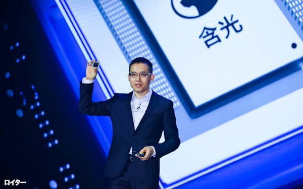 中国・杭州市で開かれたクラウドコンピューティングの会議で最新のAI半導体を公表するアリババCTOの張建鋒氏=ロイター