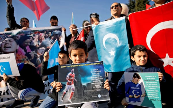 14日、イスタンブールでエジル選手の写真を掲げて中国に抗議するウイグル人の少年ら=ロイター