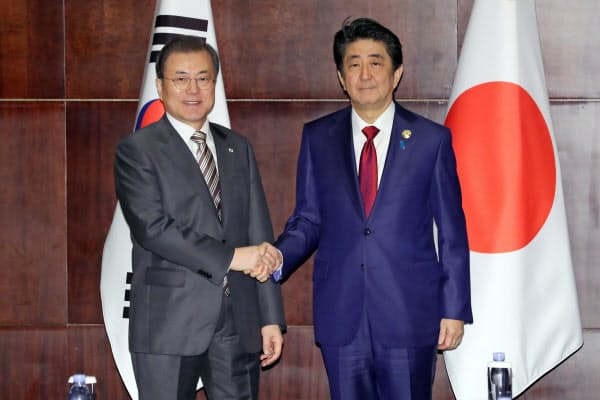 24日、首脳会談で握手する安倍首相と韓国の文大統領(中国・成都)=AP