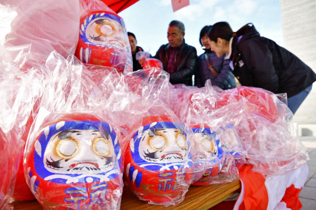 福島県双葉町の伝統行事「ダルマ市」の露店に並ぶだるま(11日午前、福島県いわき市)=共同 福島県双葉町の伝統行事「ダルマ市」の露店に並ぶだるま(11日午前、福島県いわき市)=共同