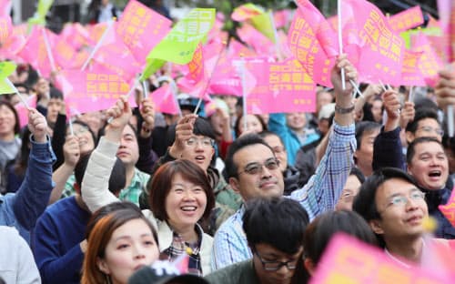 開票結果を報じるニュース速報に喜ぶ民進党の支持者(11日、台北市)=小高顕撮影