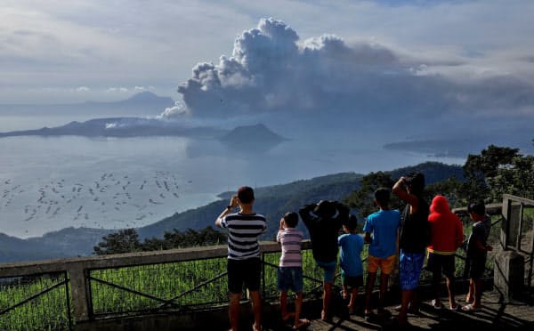 噴煙を上げるタール火山を見る人々(13日、フィリピン・バタンガス州)=ロイター