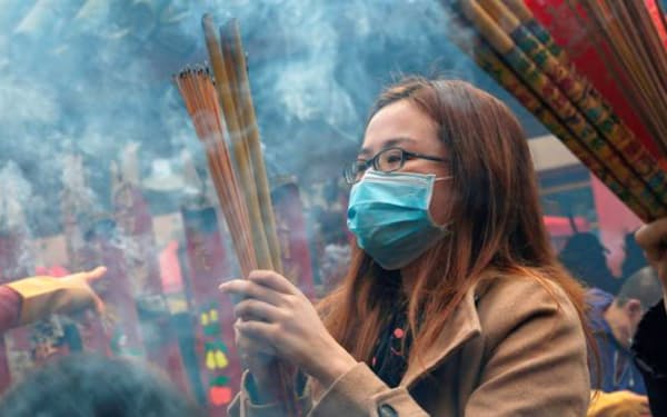 香港の寺院で旧正月に香をたく女性。香港は新型肺炎対策で緊急事態を宣言した=ロイター