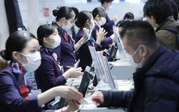 マスクをつけて応対する日本航空のスタッフら（27日、羽田空港国際線ターミナル）