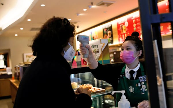 客の体温を測るコーヒー店員（30日、北京）=ロイター