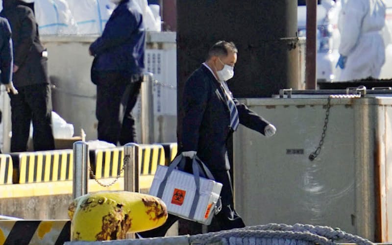乗船者から採取した検体とみられる箱を運ぶ男性(5日午前、横浜港)=共同 乗船者から採取した検体とみられる箱を運ぶ男性(5日午前、横浜港)=共同