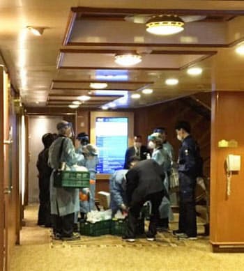 横浜・大黒ふ頭沖に停泊中のクルーズ船「ダイヤモンド・プリンセス」の船内で作業する検疫官とみられる担当者ら(4日未明、乗客提供)=共同
