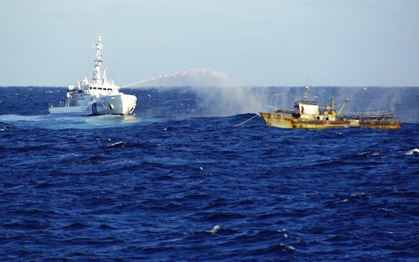 日本海の大和堆周辺で北朝鮮漁船（右）に放水する海上保安庁の巡視船（2019年11月）=同庁提供・共同