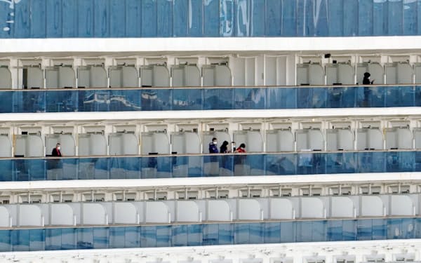 横浜港に停泊中のクルーズ船「ダイヤモンド・プリンセス」のベランダで過ごす乗客（20日）=共同