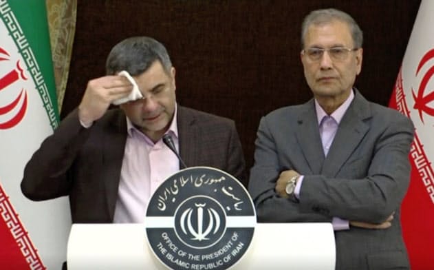 24日、記者会見中に額の汗を拭うイランのハリルチ保健省副大臣(左)。その後、新型コロナウイルス感染が確認された=AP 24日、記者会見中に額の汗を拭うイランのハリルチ保健省副大臣(左)。その後、新型コロナウイルス感染が確認された=AP