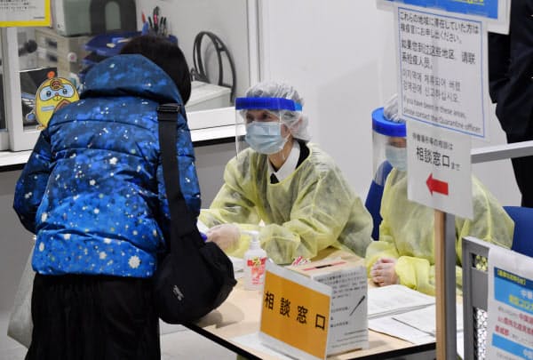 韓国からの便で成田空港に到着した入国者(左)に聞き取り調査を行う検疫官(9日午前)
