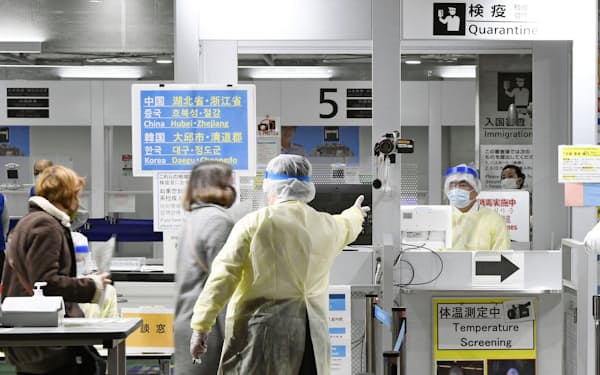 韓国から成田空港に到着した乗客を誘導する検疫官（手前、9日）