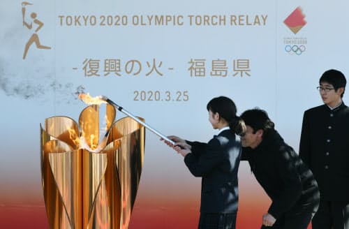 「復興の火」として地元の中学生により聖火皿にともされる東京五輪の聖火(25日、福島県いわき市)